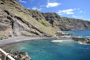A coastal road curving along a cliffside with clear blue waters and rocky terrain.