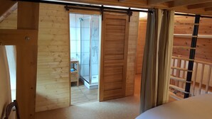 A wooden interior with a sliding door leading to a bathroom with a shower and toilet. - Gîte "le Marité", 4 people (Sartilly)