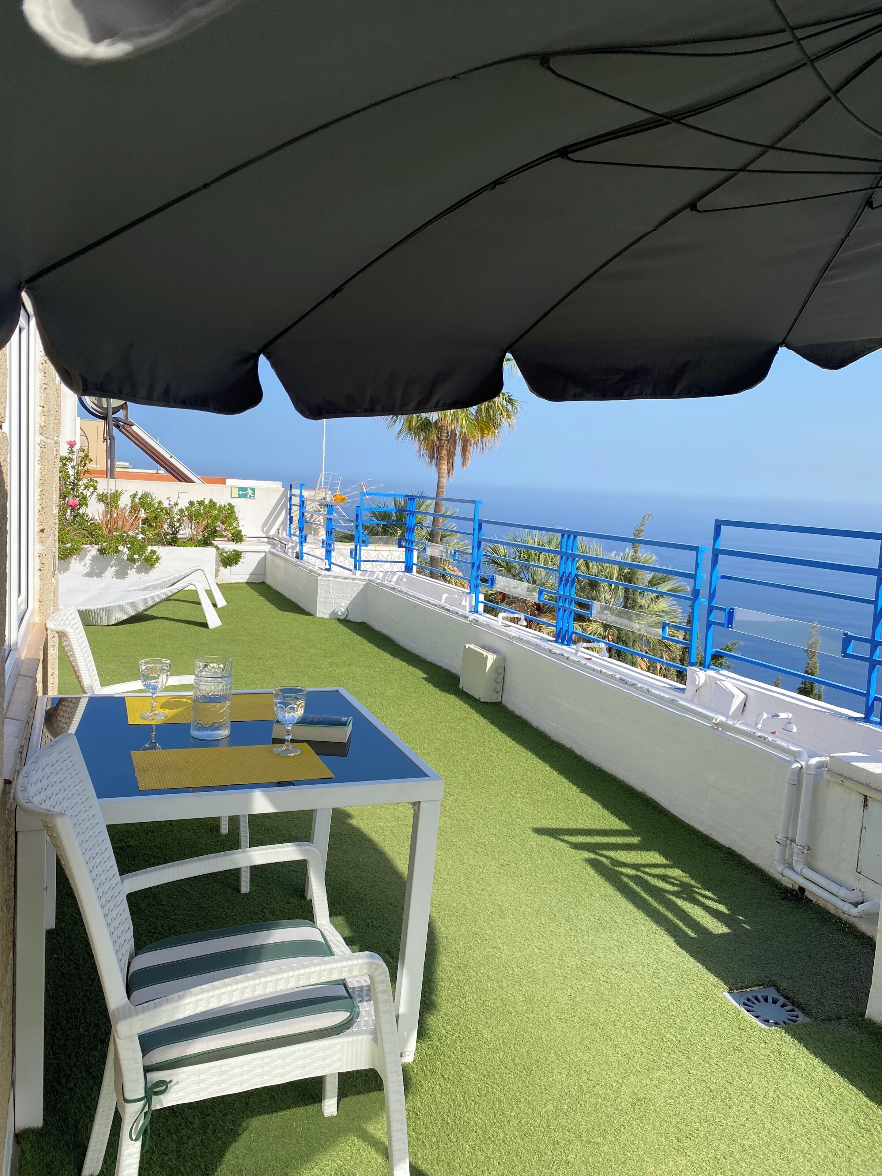 A terrace with a table, chairs, and a view of the sea.