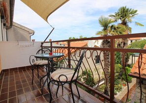 Un balcon avec une table et des chaises, une vue sur le quartier et un palmier.