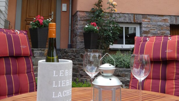 A table set with a bottle, glasses, and a lantern, with a stone wall and a building in the background. - Romantic four-star holiday home in the style of a country-house (Pommern)