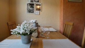 A dining table with a flower arrangement, wine glasses, and a metal pitcher. There are two wooden chairs and a small table on the right. - Romantic four-star holiday home in the style of a country-house (Pommern)