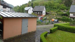 A residential area with houses, a paved driveway, and a hillside with vegetation. - Romantic four-star holiday home in the style of a country-house (Pommern)