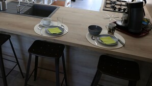 Una cocina moderna con encimera de madera, un lavamanos y dos taburetes negros.