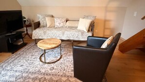 A cozy living room with a sofa, a coffee table, a TV, and a chair.