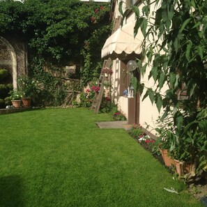 A well-maintained garden with a lawn, potted plants, and a wooden structure.