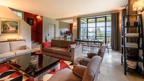 Una sala de estar moderna con un sofá, sillones, una mesa de centro y una zona de comedor con vistas al exterior.