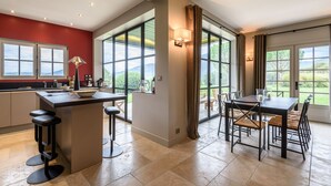 Una cocina moderna con una isla central, taburetes de bar y un comedor con mesa y sillas.