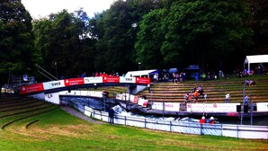 A race track with spectator stands and a grassy area.