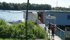 A dock with a boat, a building with a sign reading "CHILL WAKE," and a person carrying a bucket.