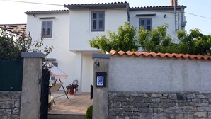 A two-story building with a white facade, numbered 14, and a stone wall with a tiled roof. - Casa di campagna per famiglie (Vodnjan)