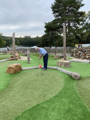 A miniature golf course with a putting green, sand traps, and a wooden fence.