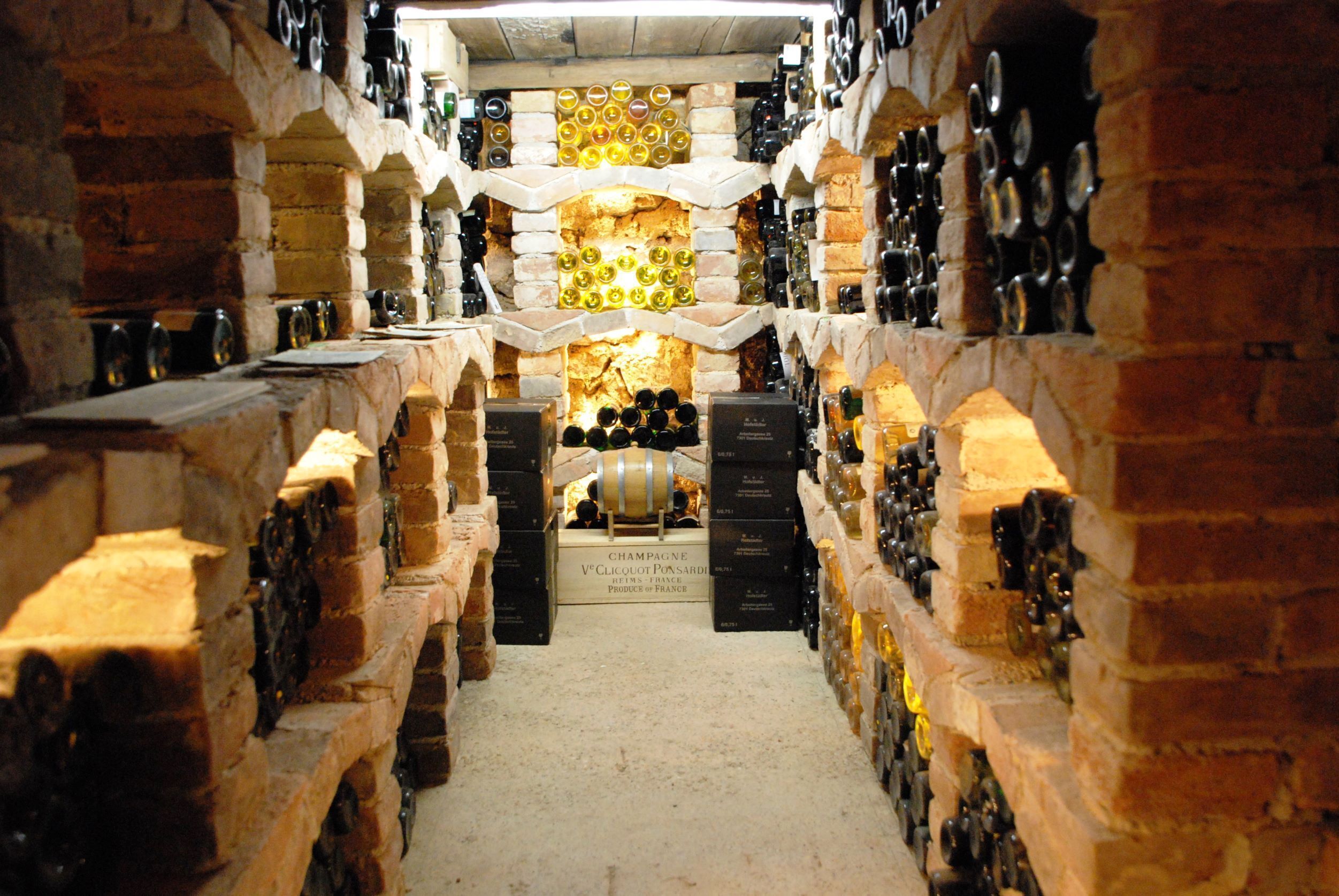 Une cave à vin avec des rangées de bouteilles et un tonneau au centre.