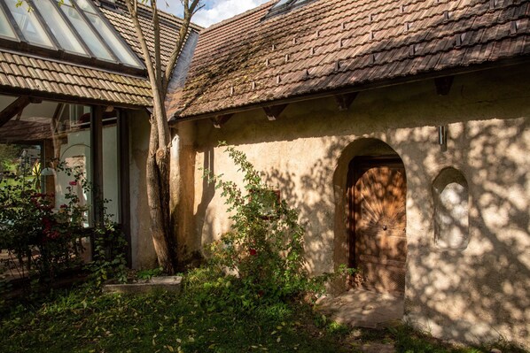 A rustic building with a tiled roof, a wooden door, and a glass window.