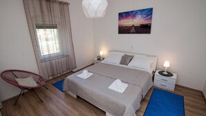 A bedroom with a bed, two bedside tables, a chair, a window with curtains, a wall-mounted picture, and a hanging light fixture. - Holiday home in Pula,2 km from the amphitheater,family-friendly,quietly,WIFI (Pula)