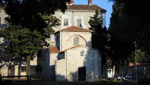 A historic building with a central arched entrance, a smaller attached structure with a tiled roof, and a large building in the background. - Holiday home in Pula,2 km from the amphitheater,family-friendly,quietly,WIFI (Pula)