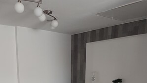 Un espace repas moderne avec une table rectangulaire, des chaises blanches et un luminaire suspendu au plafond.