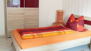 A bedroom with a bed, a wardrobe, and a nightstand.