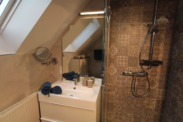 A bathroom with a skylight, a shower, a sink with toiletries, and a mirror. - Four-star accommodation in Friesenhörn, in a quiet, south-facing location, right on the dike (Horumersiel)
