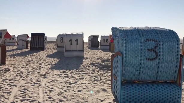 A beach with numbered beach chairs and umbrellas, indicating a rental area. - Four-star accommodation in Friesenhörn, in a quiet, south-facing location, right on the dike (Horumersiel)