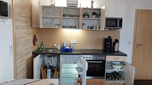 Uma cozinha compacta com micro-ondas, fogão e frigorífico, com armários e pia.