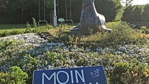 Escultura de um cão numa área gramada, com uma placa que diz 'MOIN MOIN'.