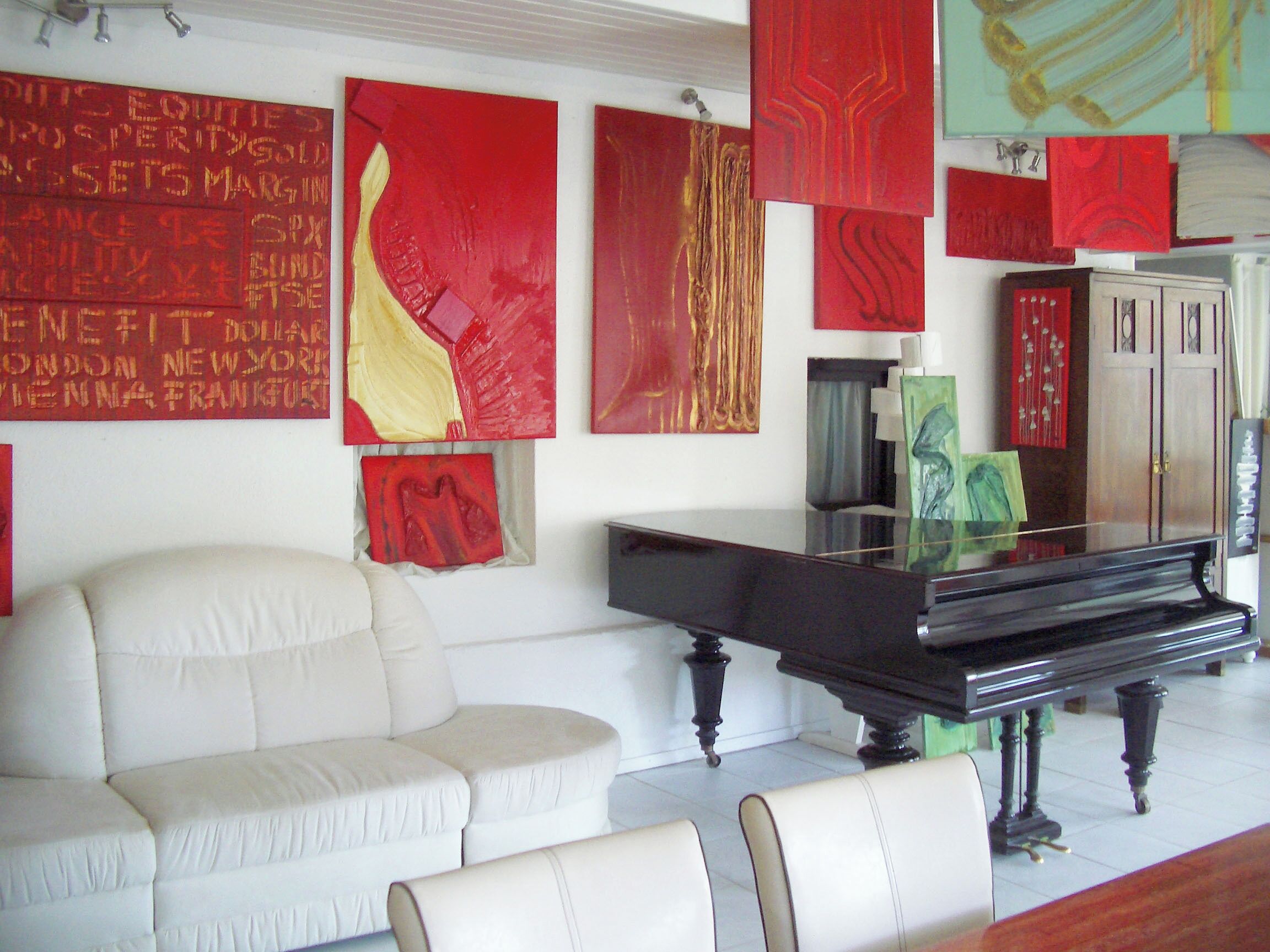 Un soggiorno con un pianoforte, un divano e opere d'arte astratta alle pareti.