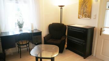 A room with a desk, a chair, a small table, a lamp, and a cabinet.