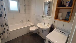 Une salle de bain équipée d’une baignoire, de toilettes, d’un lavabo et d’un lave-linge.
