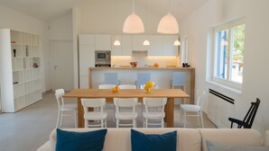 A modern kitchen with white cabinets, a wooden dining table, and pendant lights. - 3000sqm plot, with 50 sqm heated pool, jacuzzi, 2 tennis courts  (Marčana)