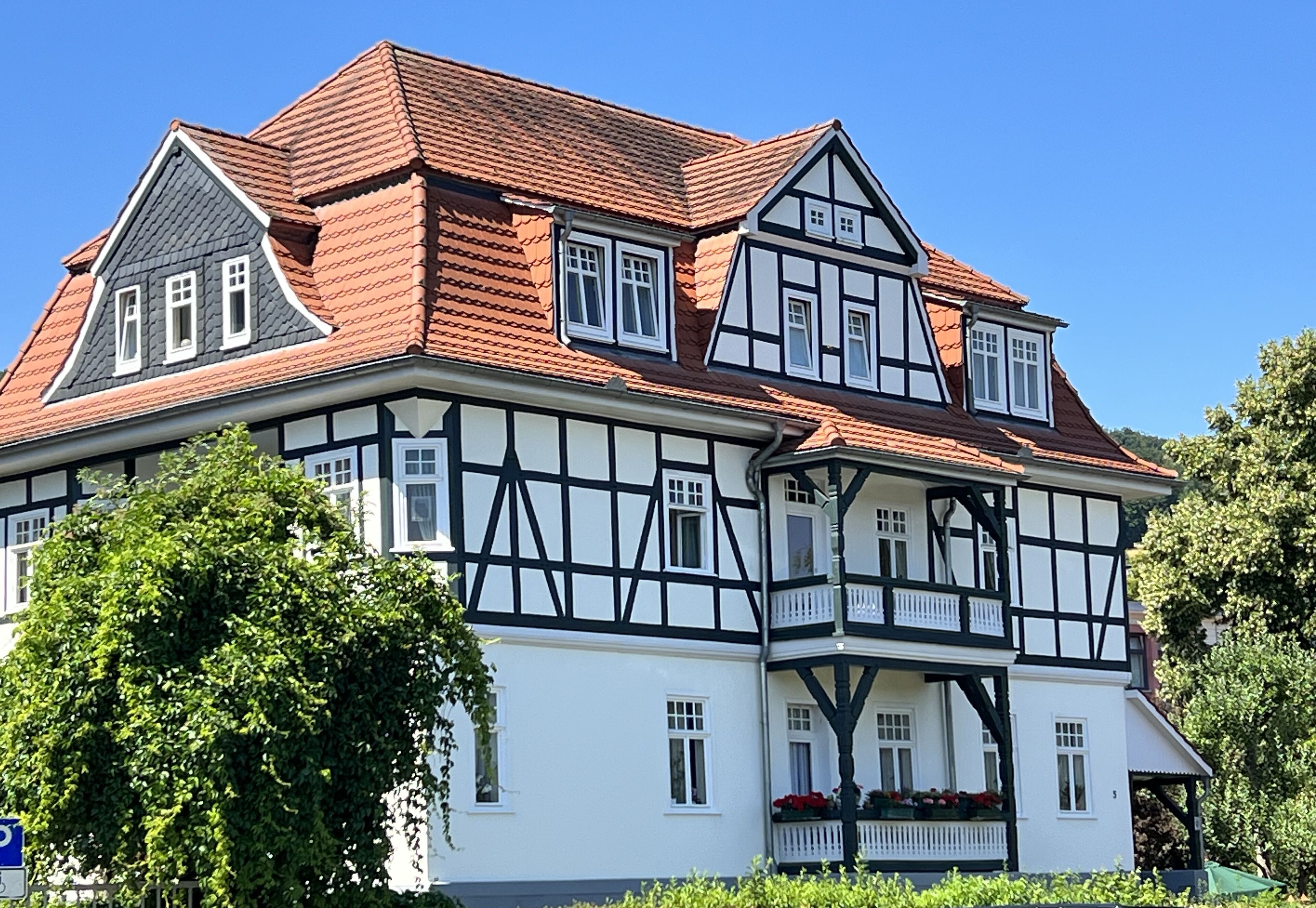 A large, two-story building with a steeply pitched roof and a mix of white and dark timber framing.