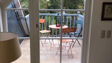 Une pièce dotée d’une grande porte-fenêtre coulissante qui donne sur une terrasse extérieure avec une table et des chaises.