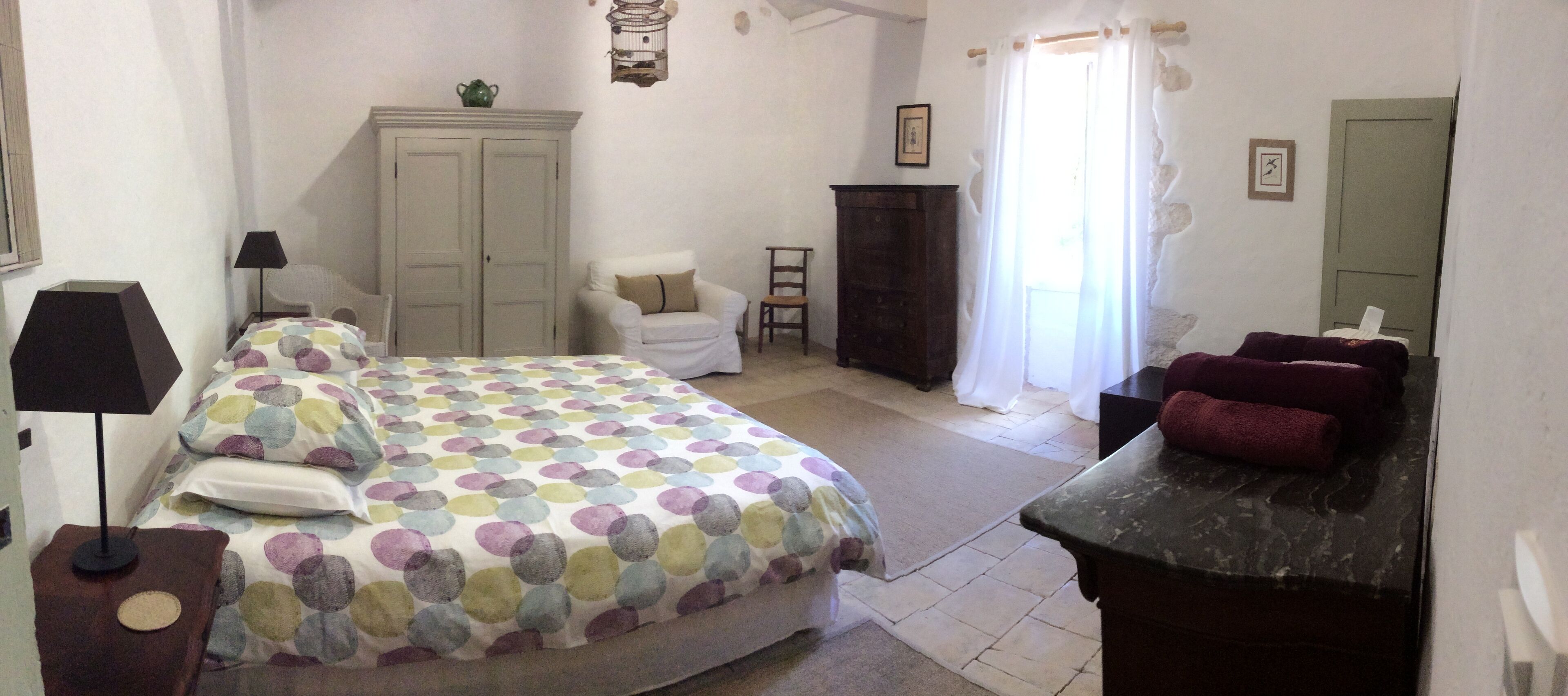 Un dormitorio con cama, silla, cómoda y espejo.