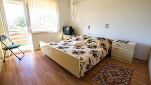 A bedroom with a bed, a chair, a TV, a dresser, and a window with curtains. - Apartment with free Wi-Fi and air conditioning (Starigrad Paklenica)