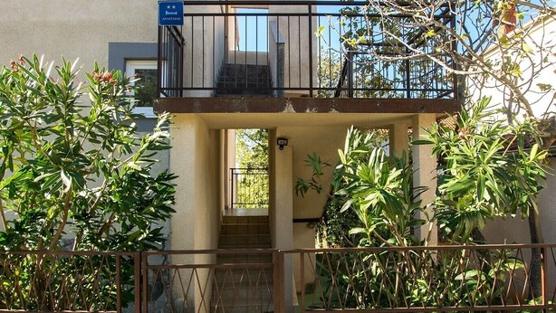 A two-story building with a balcony, stone wall, and greenery. - Apartment with free Wi-Fi and air conditioning (Starigrad Paklenica)