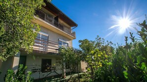 A two-story building with a balcony, surrounded by greenery. - Apartment with free Wi-Fi and air conditioning (Starigrad Paklenica)