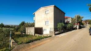 A two-story building with a flat roof, a garage, and a small garden area. - Apartment with free Wi-Fi and air conditioning (Starigrad Paklenica)