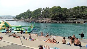 A waterfront area with inflatable water toys and people relaxing on the shore. - Apartment DiSente °2 with Sea view  (Krk)