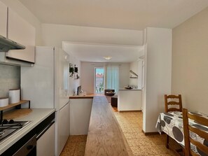 Una cocina moderna con una isla central, un comedor con mesa de madera y vistas al exterior por una ventana.