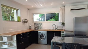 Una cocina funcional con lavadora, un lavamanos y una zona de comedor con mesa y sillas.