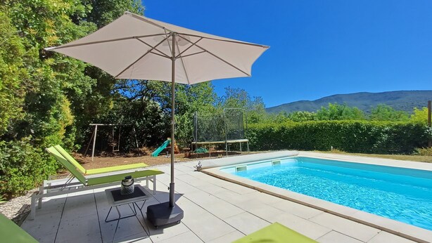 Una piscina con zona de patio, que incluye una mesa y sillas, además de un columpio.