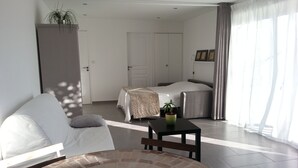 Una habitación de hotel moderna con una cama, un sofá, una mesita y una planta en maceta.