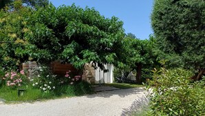 Un camino de grava que conduce a un edificio blanco con un muro de piedra y una valla de madera.