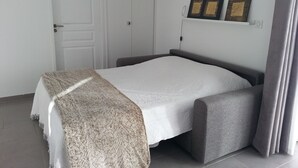Un dormitorio ordenado con una cama, una mesita de noche, un armario y dos cuadros colgados en la pared.