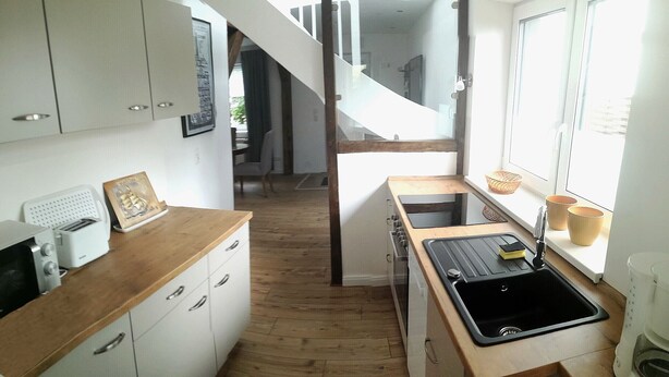 A compact kitchen with white cabinets, a wooden countertop, a black sink, and a window with a view.