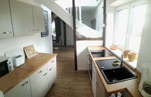 A compact kitchen with white cabinets, a wooden countertop, a black sink, and a window with a view.