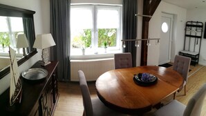 A dining area with a wooden table, chairs, a small decorative bowl, and a window with curtains.