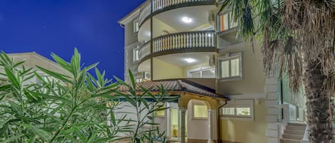 A multi-story building with balconies, a covered entrance, and a tiled courtyard.