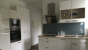 Une cuisine moderne avec des armoires blanches, un four encastré, un four à micro-ondes et un évier en acier inoxydable.