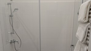 Un baño con cabina de ducha de vidrio, un lavabo y un perchero para toallas.
